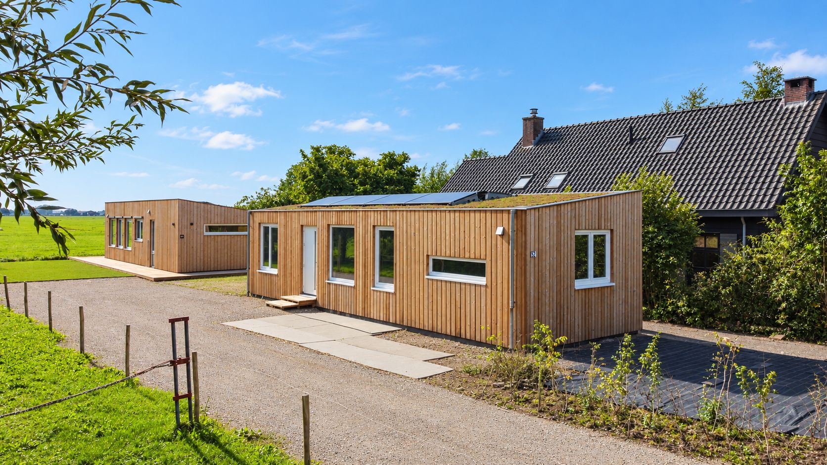 Twee houten Plexatwoningen met groen dak aan de Doetseweg in Giessenburg, naast een woonboerderij