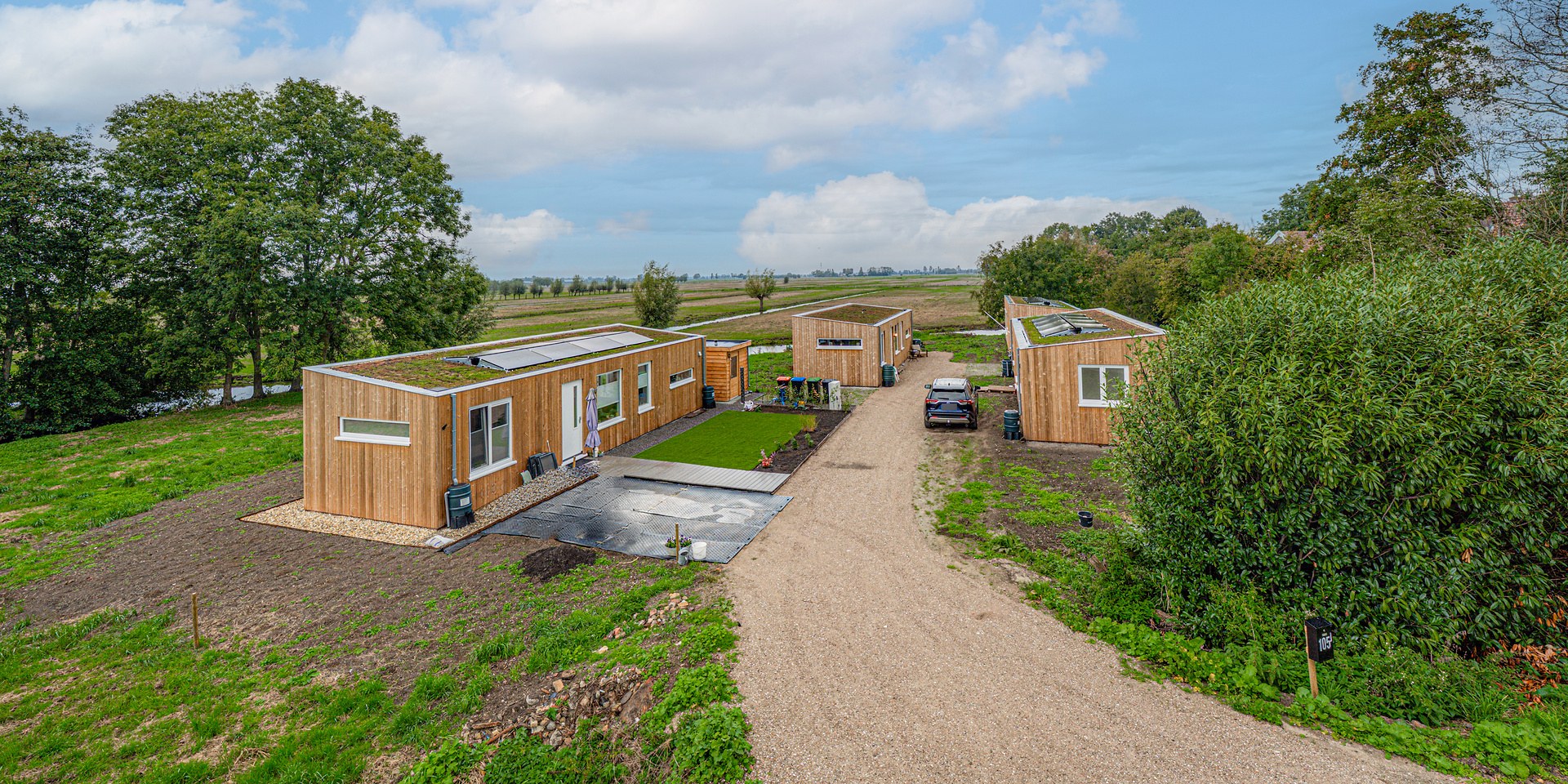 Drie Plexat-woningen van Groundshare op een groene kavel met grindpad